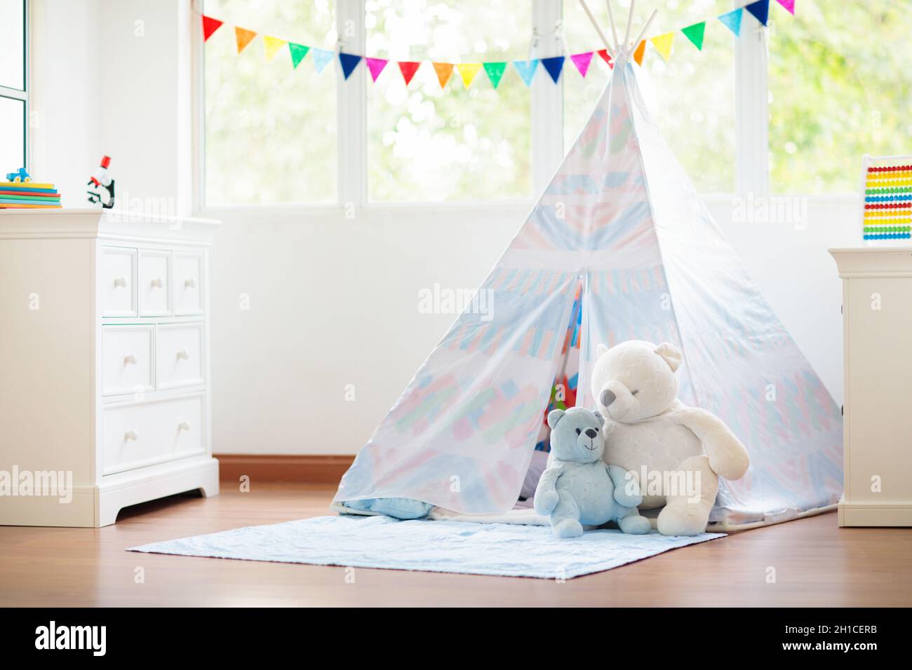 Kids room with teepee tent. White sunny bedroom for children. Cozy light interior for kid nursery or playroom. Stock Photo