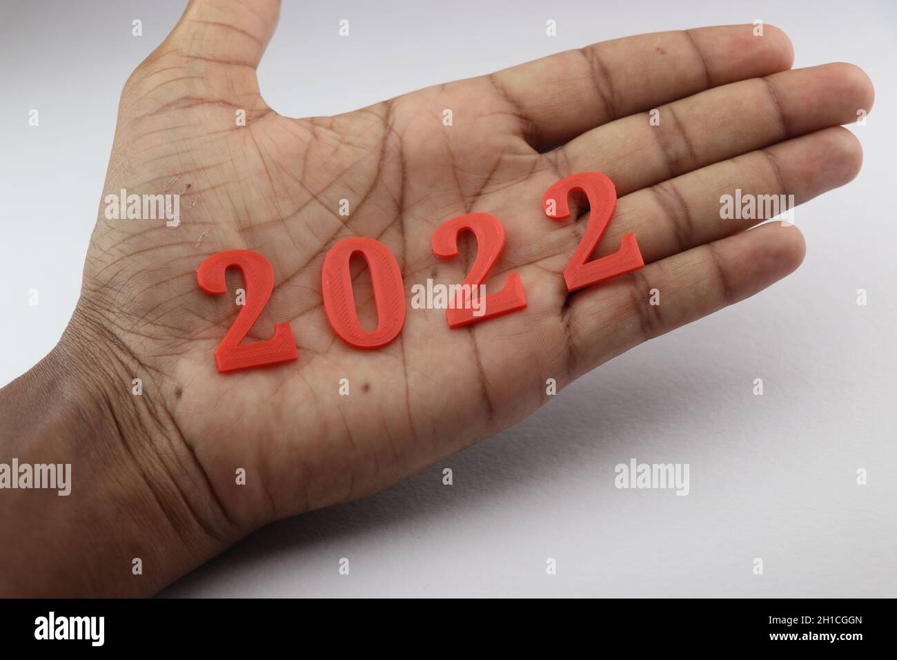 Happy new year wishes concept shown by holding 2022 in hand. A unique way of representing the new year 2022 Stock Photo