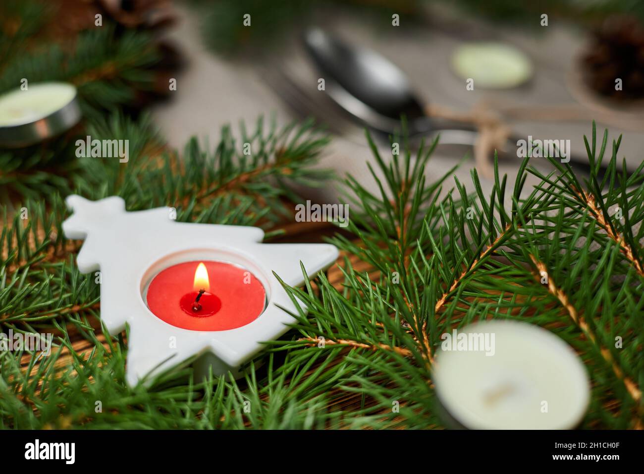 Burning candle in a Christmas tree on a served Christmas table against ...