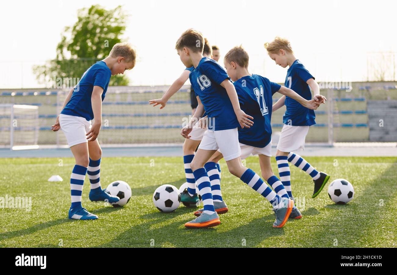 Football Team in Blue Soccer Uniforms on Training Class With Balls. Kids Kicking Balls on Grass Venue. Soccer Class For School Kids Stock Photo