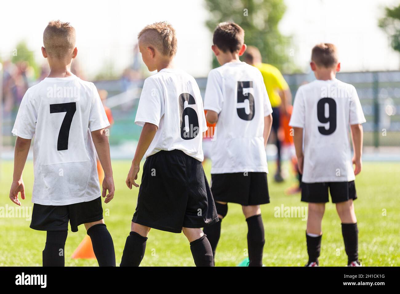 Football Boys Standing on a Sideline on Football Pitch. Kids Playing Football School Tournament on a Summer Day. Kids in White Soccer Shirts with Blac Stock Photo