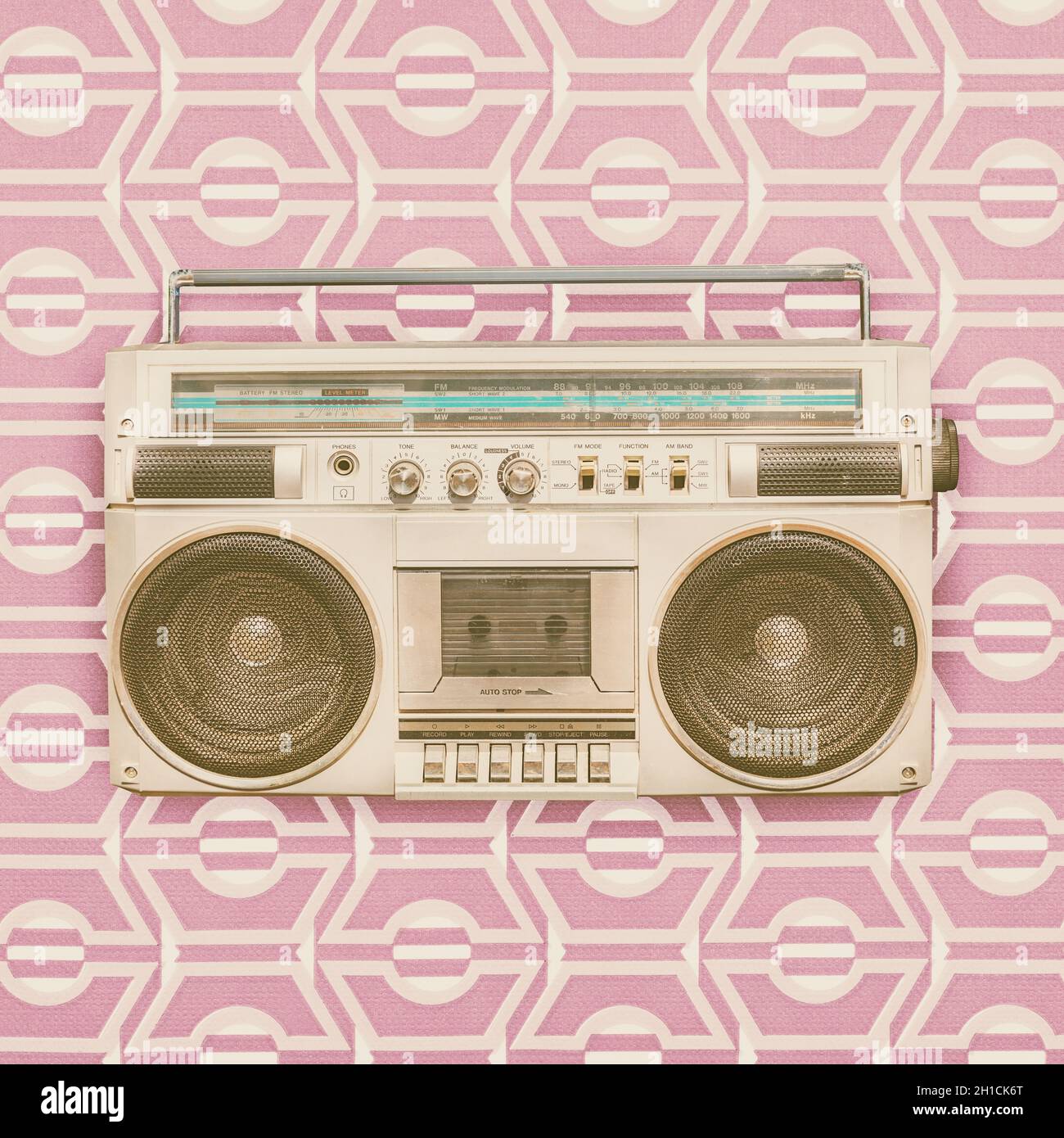 Retro styled image of an eighties portable radio cassette player in front of vintage wallpaper Stock Photo