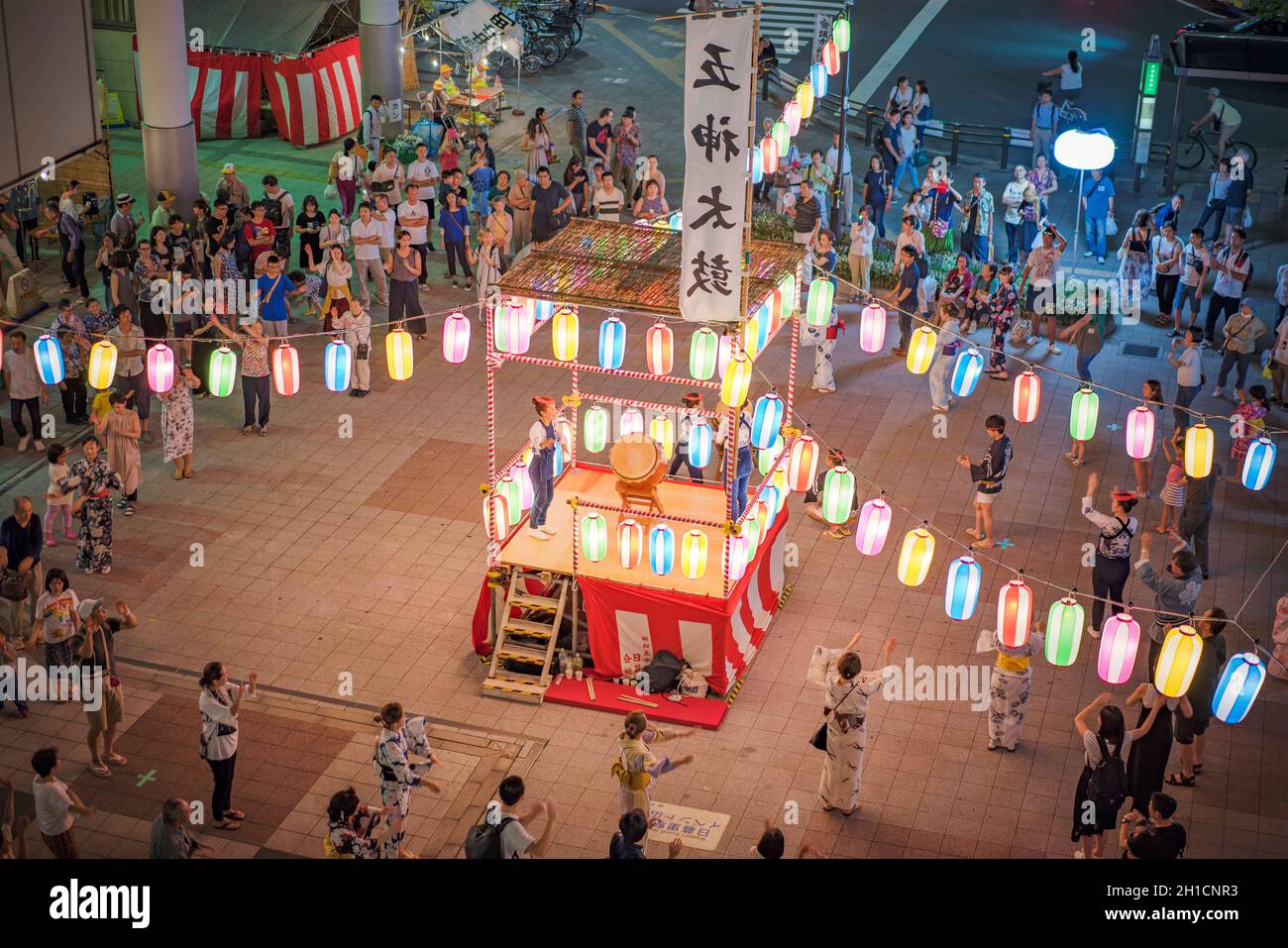 View of the square in front of the Nippori train station decorated for the Obon festival with illuminated paper lanterns  in the summer night with a y Stock Photo