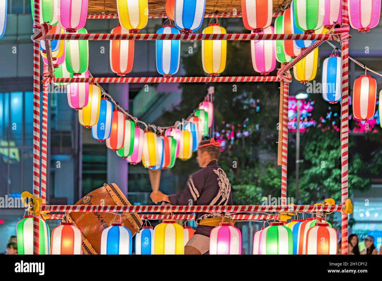 View of the square in front of the Nippori train station decorated for the Obon festival with a yagura tower illuminated with paper lanterns where a m Stock Photo