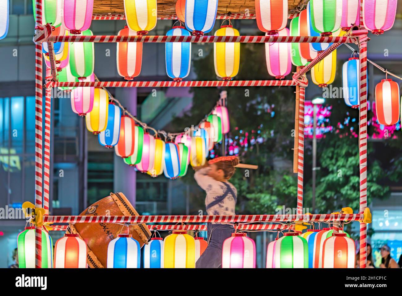 View of the square in front of the Nippori train station decorated for the Obon festival with a yagura tower illuminated with paper lanterns where a g Stock Photo