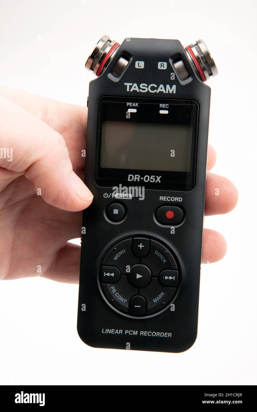 HUETTENBER, GERMANY - FEBRUARY 03, 2020: Male Hand hold Tascam DR-05X Digital Audio recorder. Portable field recorder on white desk. Stock Photo