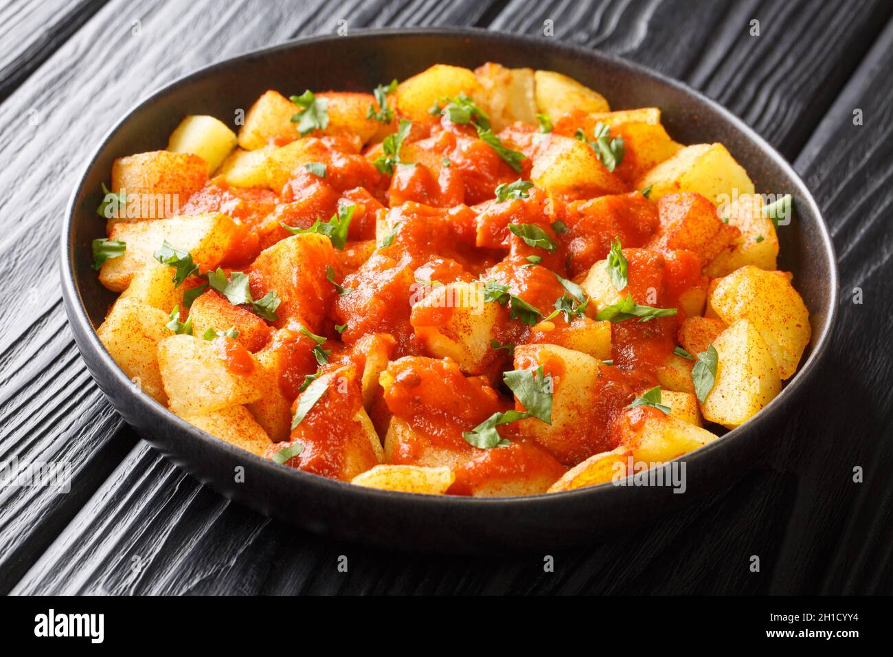 Patatas Bravas recipe fried potatoes with bravas sauce close up in the plate on the table. Horizontal Stock Photo