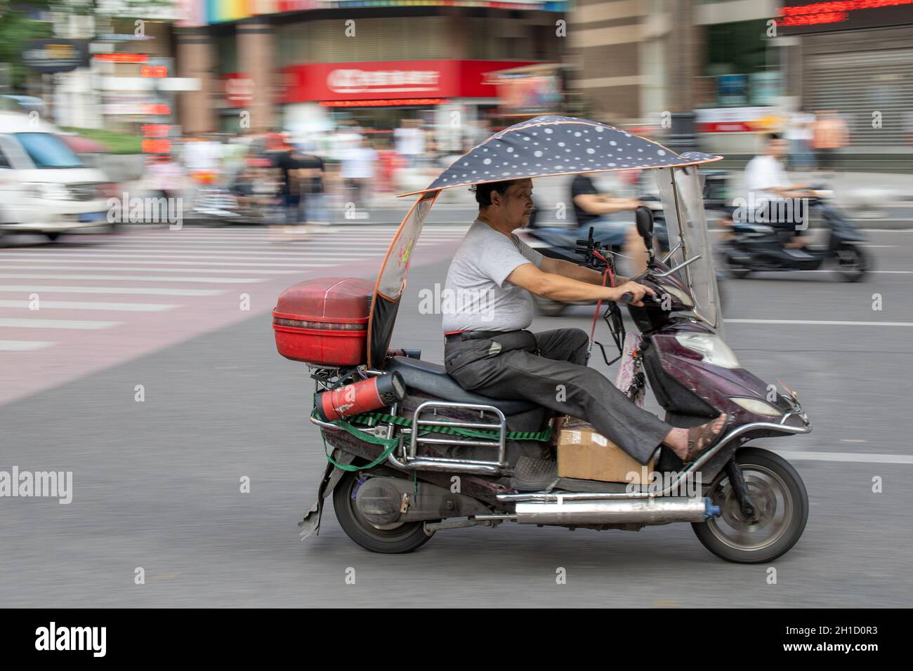 Chongqing, China - August 2019 : Man riding dangerously fast in a scooter on the congested street Stock Photo