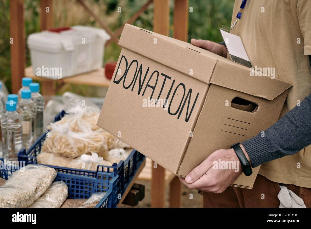 Male volunteer holding packed donation box while standing by table with