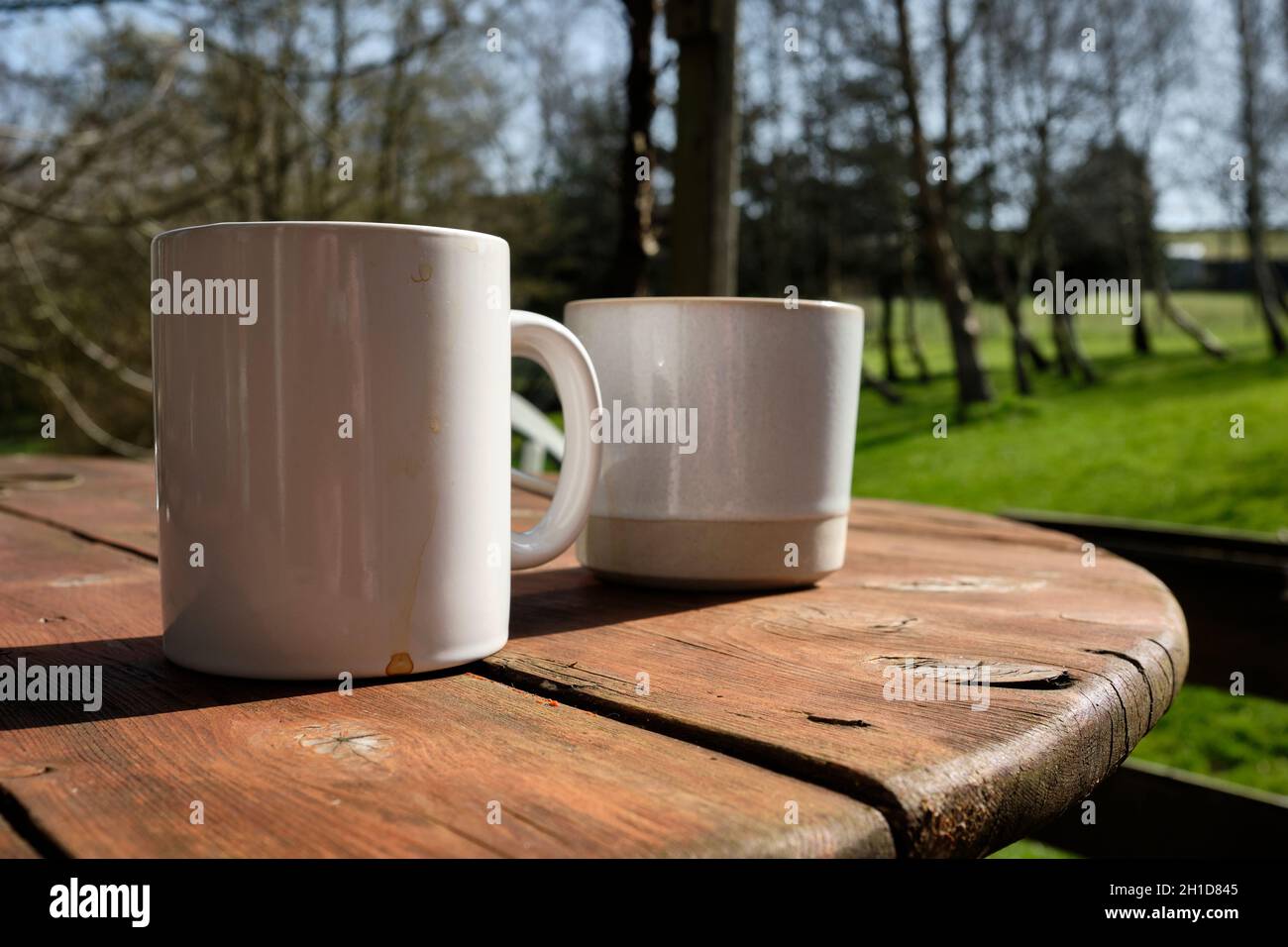 Two mugs on an outdoor wooden table Stock Photo