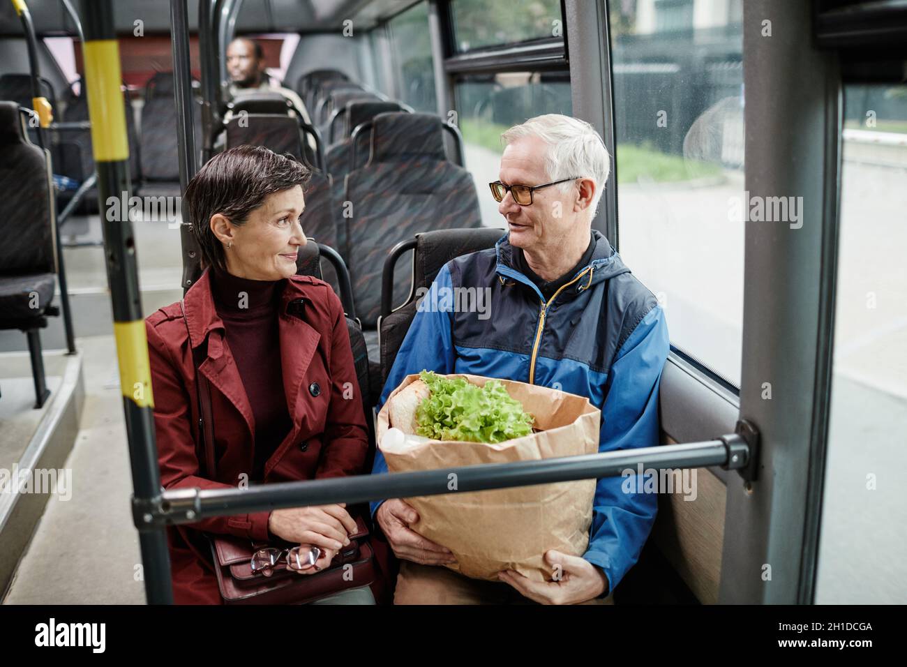 Portrait of adult couple chatting in bus while traveling by public transport in city, copy space Stock Photo