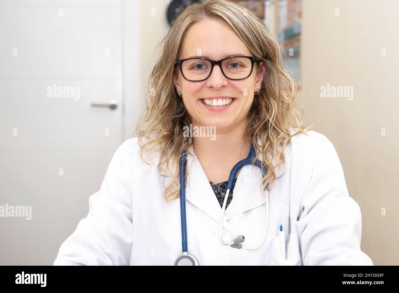 Confident female doctor posing smiling in her office . Stock Photo