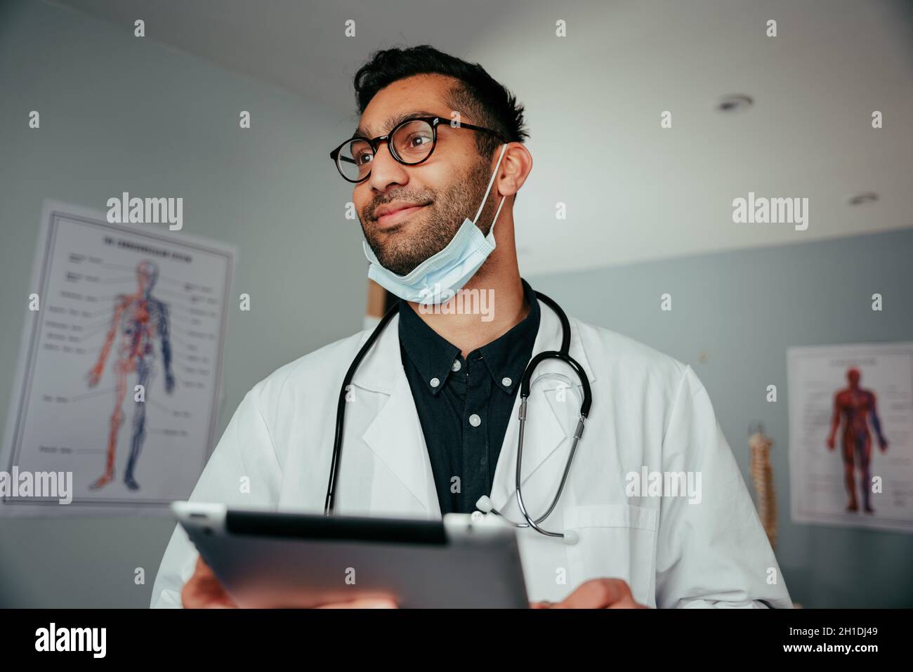 Mixed race male surgeon standing in office holding digital tablet Stock Photo