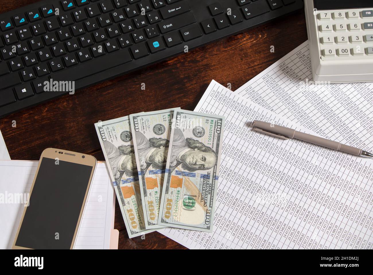 Money dollars are on the desktop in the office next to the computer, phone, documents and cash register.Obligation to pay wages and debts in the compa Stock Photo