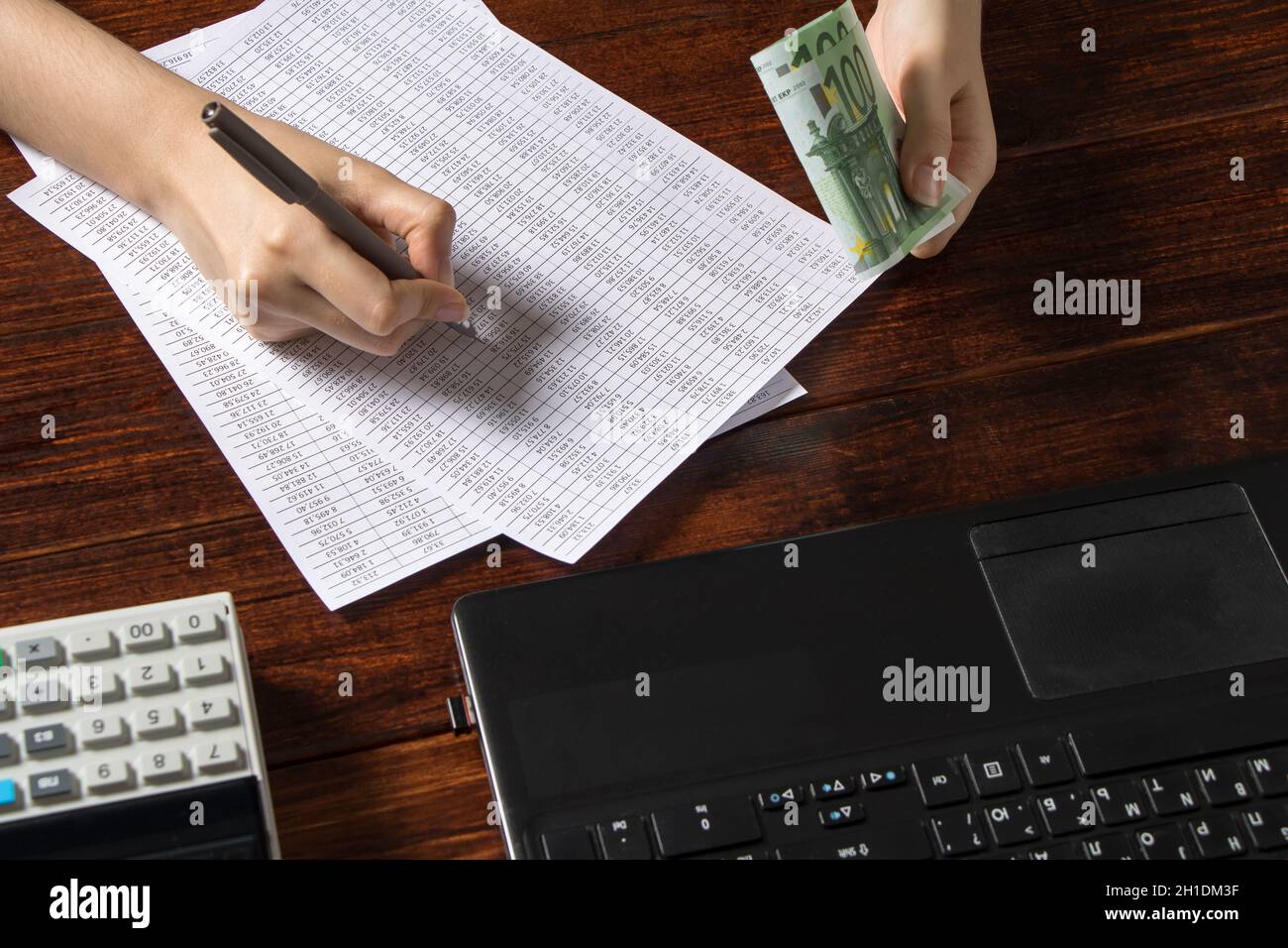 Obligation to pay wages and debts in the company.A cashier holds money Euro over an office work space with documents, a cash register,a phone,and a co Stock Photo