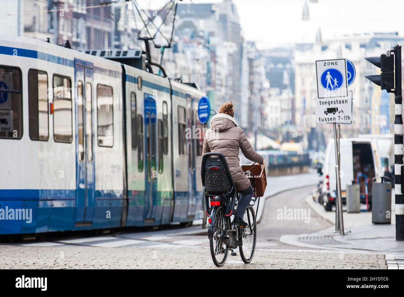 AMSTERDAM, NETHERLANDS- MARCH, 2018: Cyclist in a cold early spring day at the Old Central district of Amsterdam Stock Photo