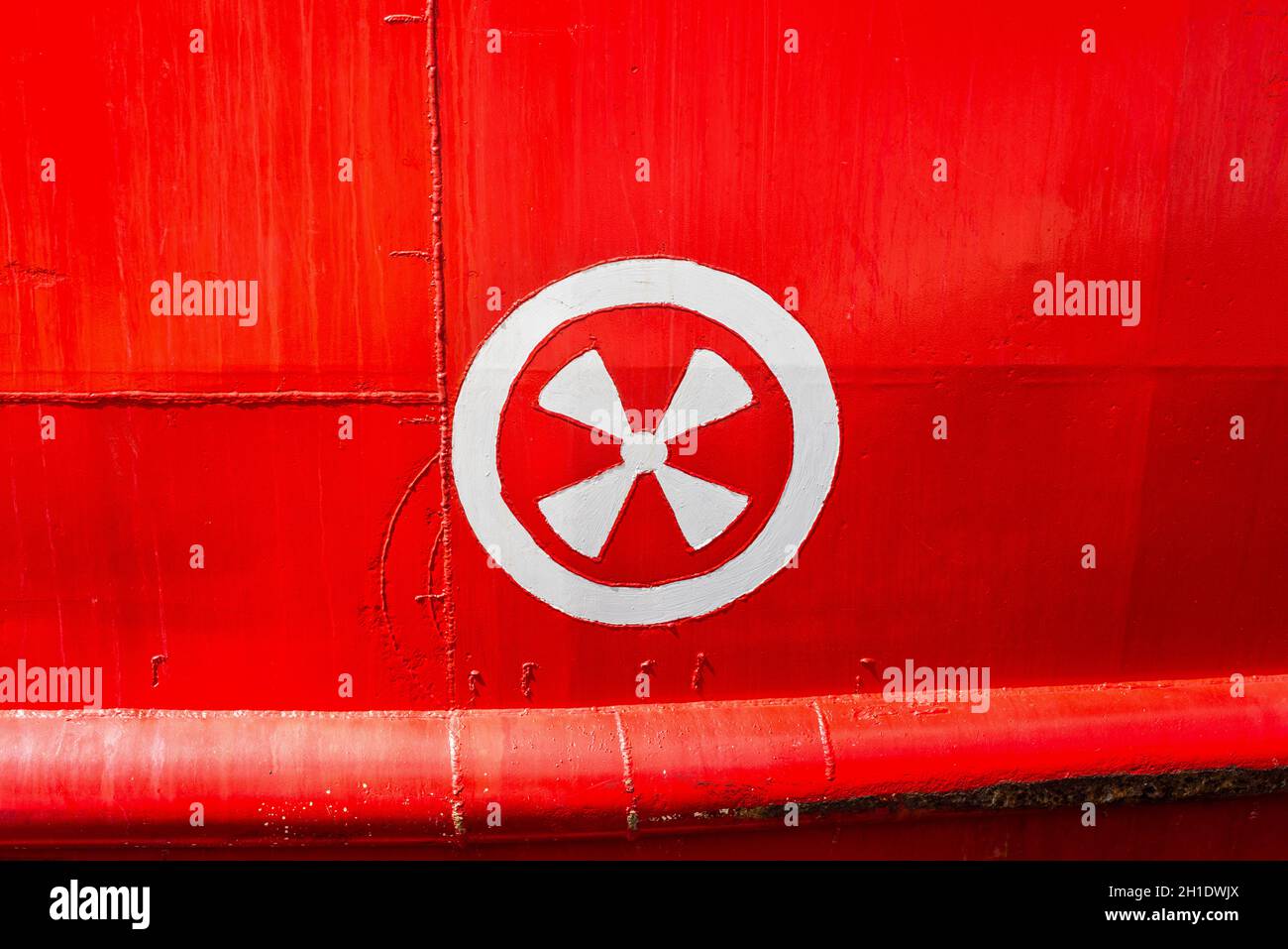 Steel Hull of red vessel in water with detail of a ship's hull markings of thruster screw position Stock Photo