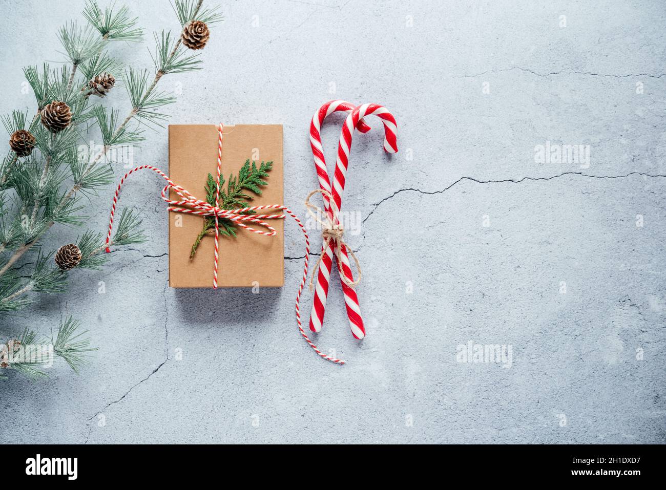 New Year composition with Christmas gift box, pine cones, and thuja branches on gray cement background with copy space Stock Photo
