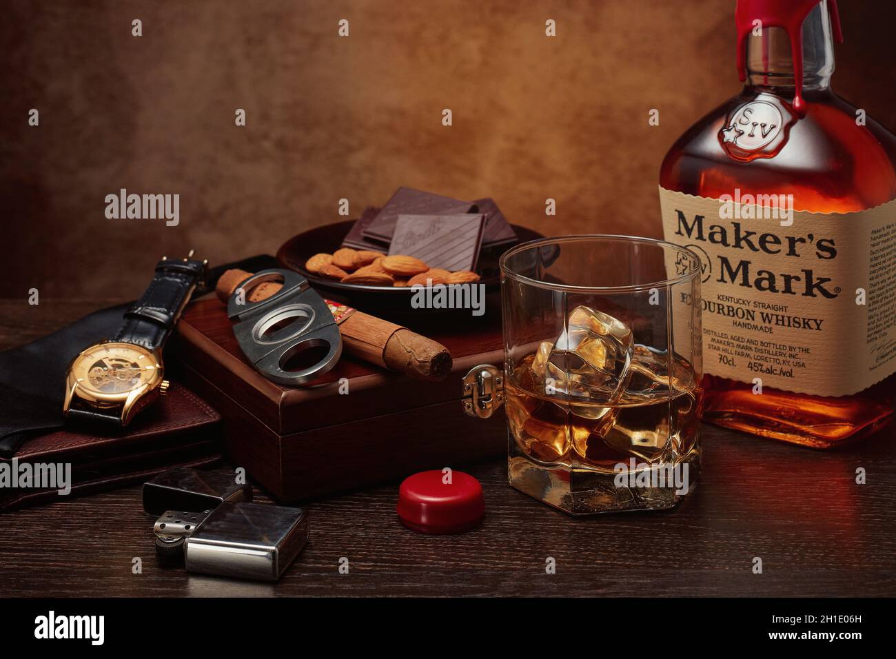 St.Petersburg, Russia - March 2020 - Still life with bottle of Maker's Mark kentucky straight bourbon whisky, glass, box with cigar, nuts and chocolat Stock Photo