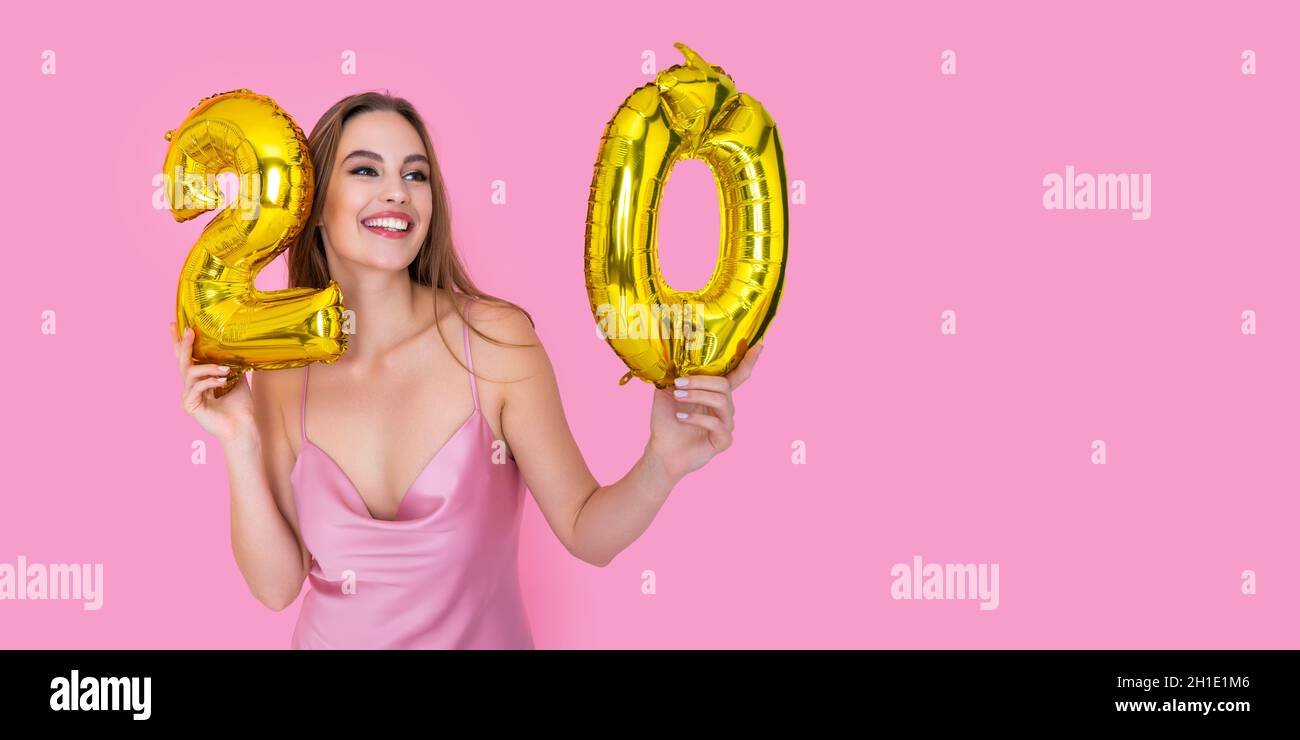 Young teenager happy girl holds gold foil balloon on pink background. BIRTHDAY PARTY concept Stock Photo