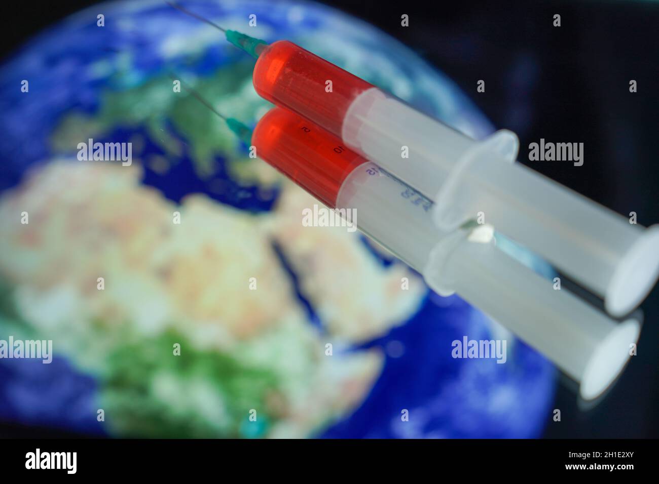 Symbolfoto, Symbolbild,einer Spritze mit Serum vor einer Weltkugel, symbolic image of a syringe in front of planet earth Stock Photo