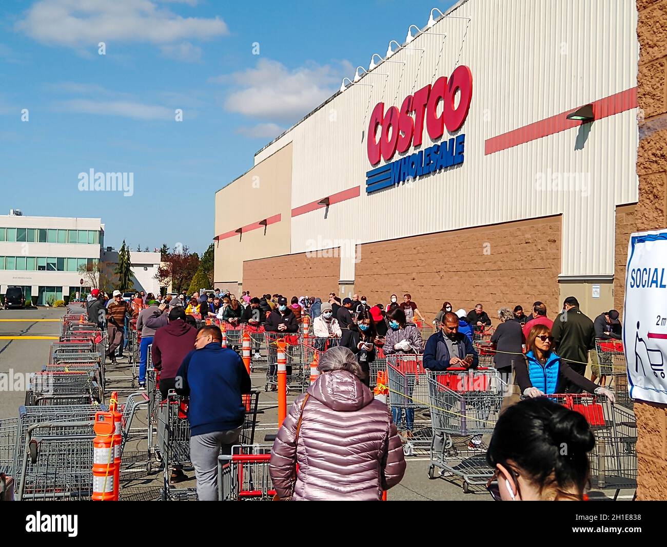 LANGLEY, CANADA - April 14, 2020. Shoppers line up at costco, in the second half of the line, to get into the store during Covid-19 on April 14, 2020. Stock Photo