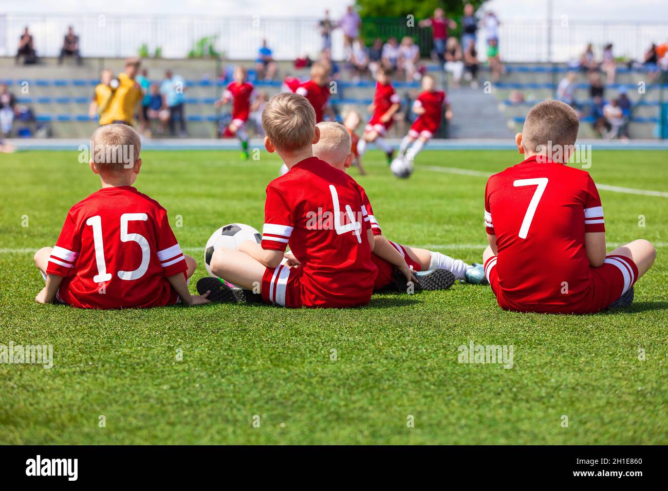 Junior Level Kids Sports Team Sitting on Grass Field. Football Soccer