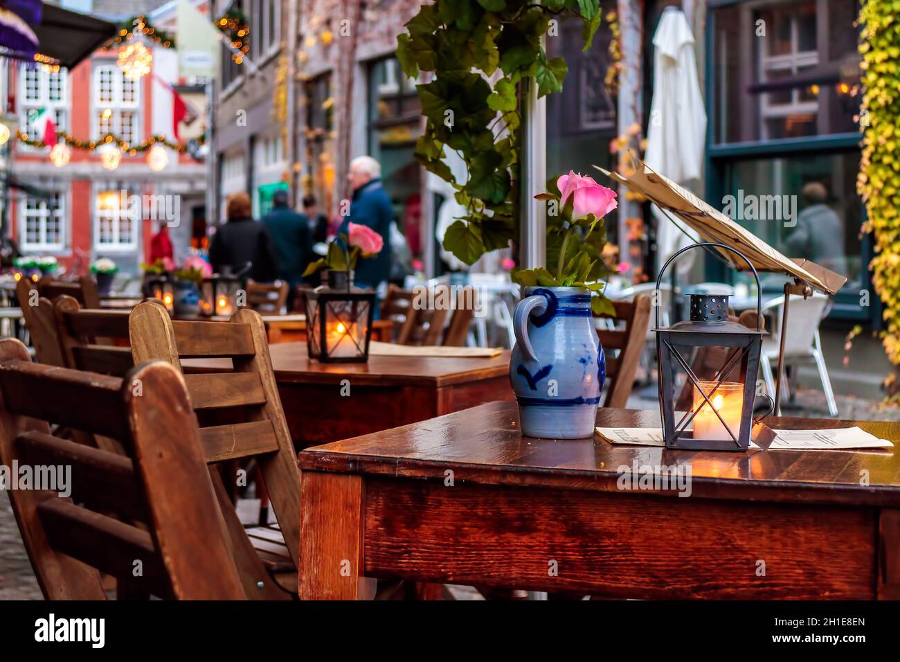 MAASTRICHT, THE NETHERLANDS - NOVEMBER 22, 2016: Empty dinner tables in front of a restaurant with tourists in the background in Maastricht Stock Photo
