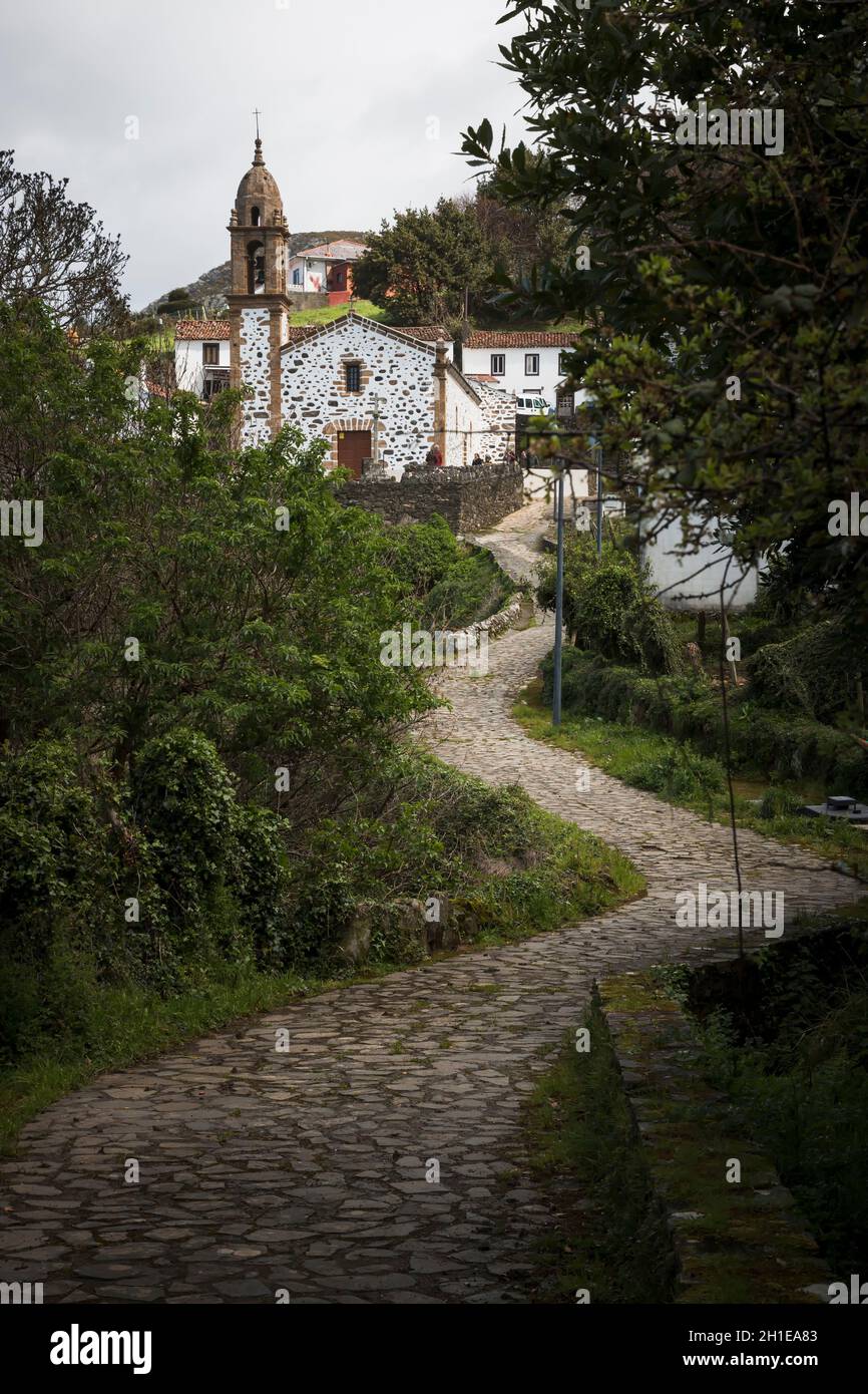 San Andres de Teixido, Spain - 01, 04, 2017: A winding, cobbled path leads to the chapel of San Andres de Teixido between trees and vegetation Stock Photo