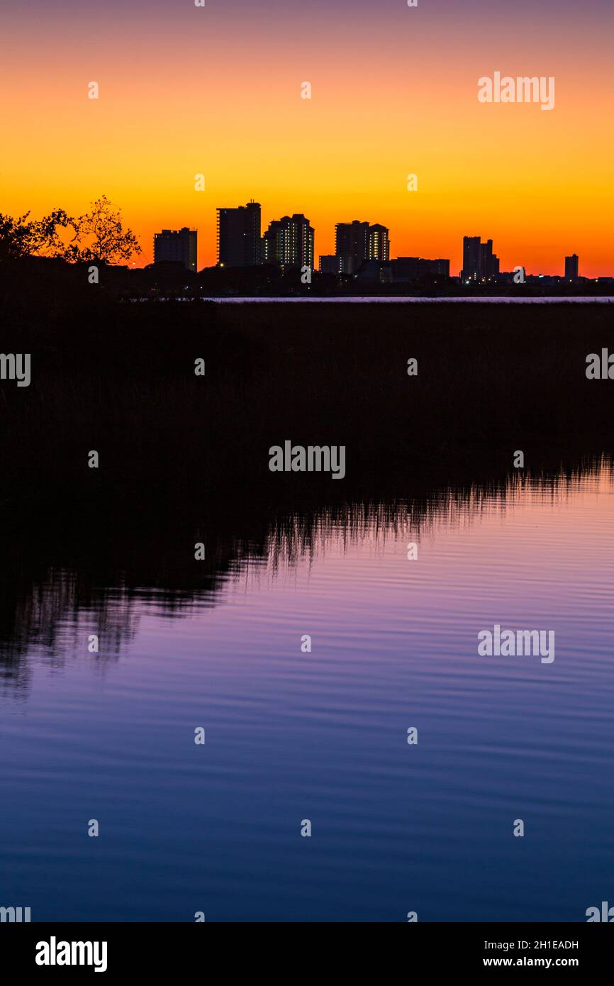 Silhouette of hotels and condominiums of Gulf Shores, Alabama behind canal after sunset in Gulf State Park Stock Photo