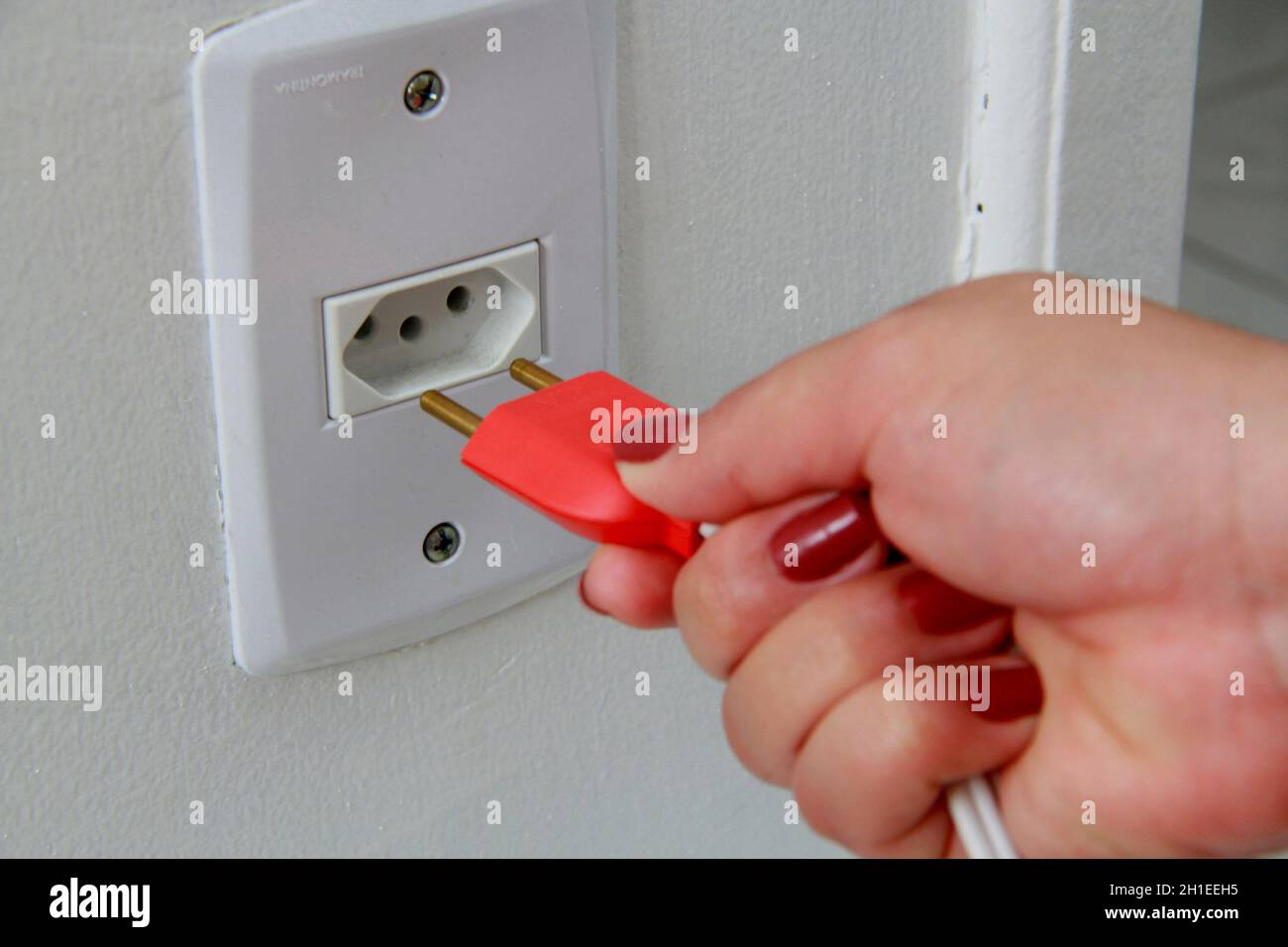 salvador, bahia / brazil november 10, 2013 hand holds power cable to plug into the outlet