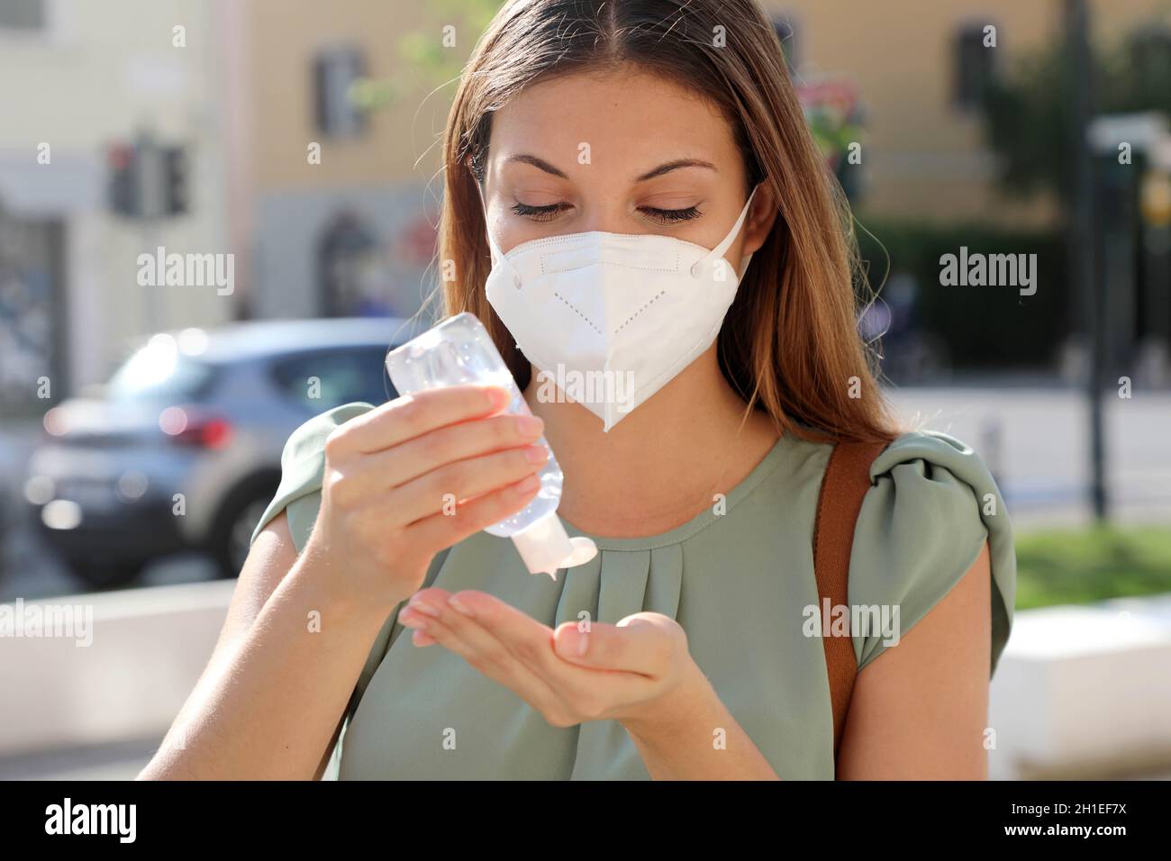 COVID-19 Pandemic Coronavirus Close up Woman with KN95 FFP2 Mask using Alcohol Gel Sanitizer Hands in City Street. Antiseptic, Hygiene and Healthcare Stock Photo