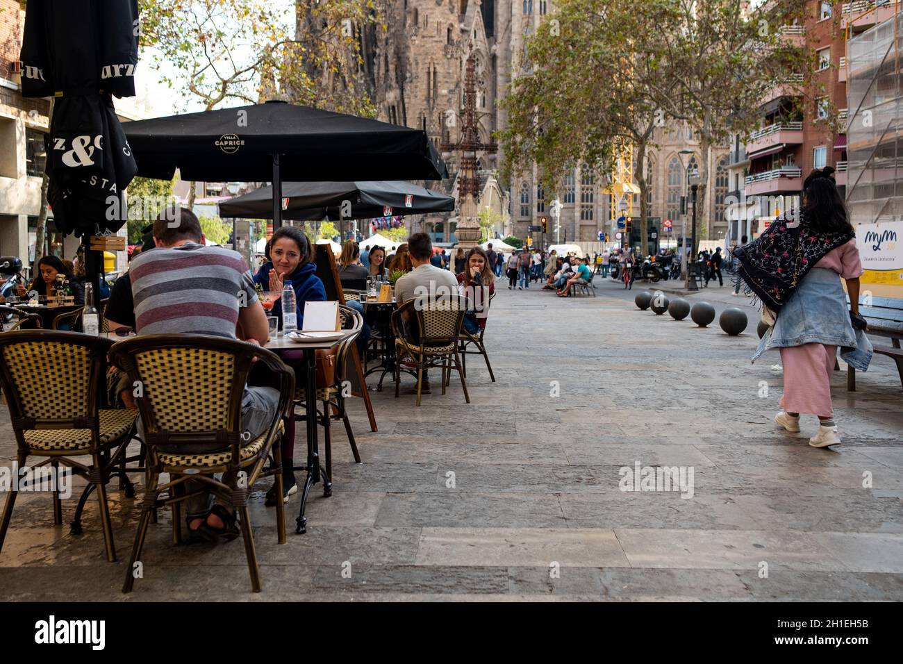 People and tourists sit at crowded restaurants terraces below the Sagrada Familia church in Barcelona, Spain on October 17, 2021. Most covid restrictions have been lifted in the country, with only the face mask being compulsory indoors. The hospitality industry is hopeful this will foster a speedy recovery (Photo by Davide Bonaldo/Sipa USA) Stock Photo
