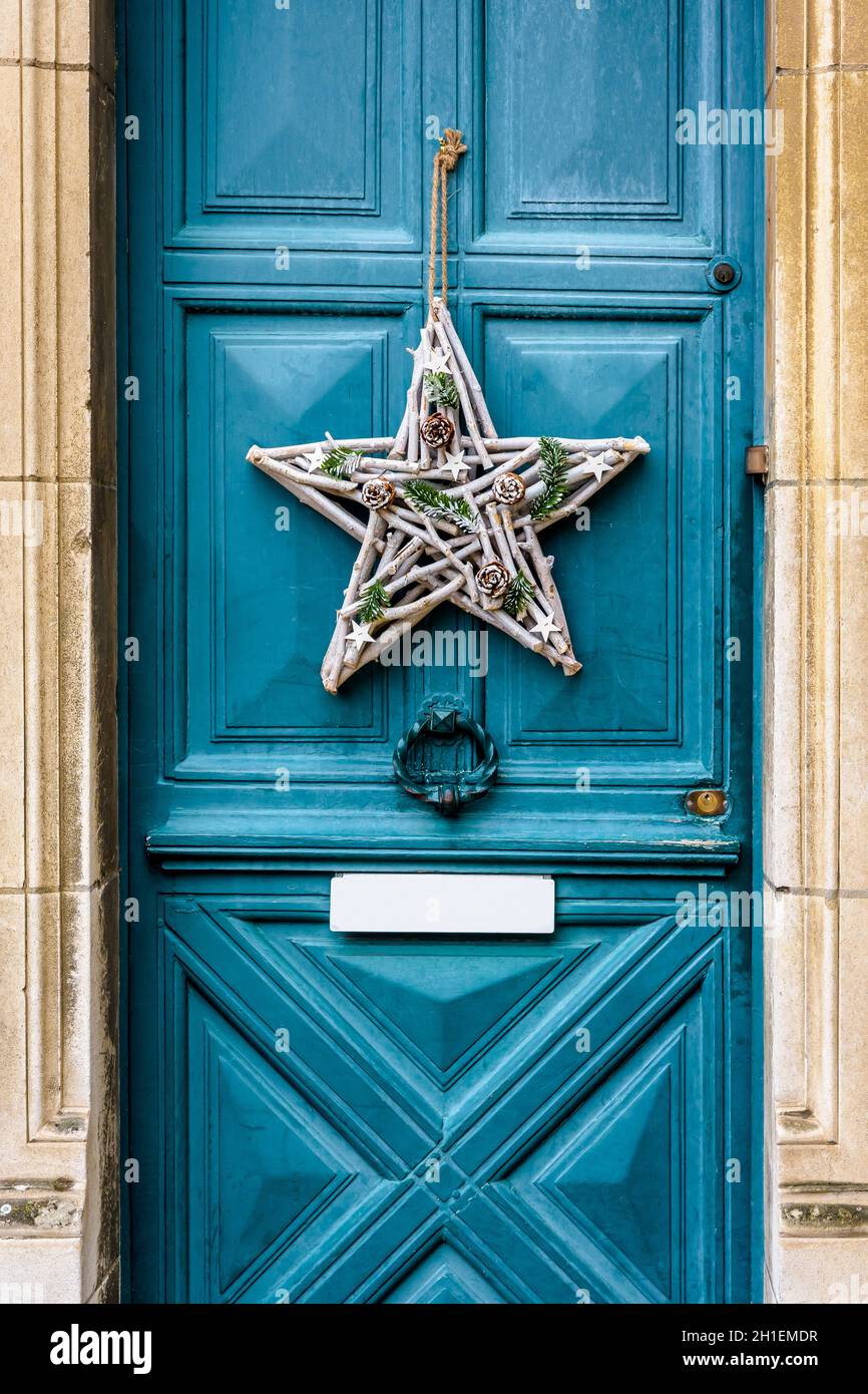 Front view of a star-shape Christmas decoration made of branches and pine  cones, hanging on the blue front door with moldings of an old townhouse  Stock Photo - Alamy