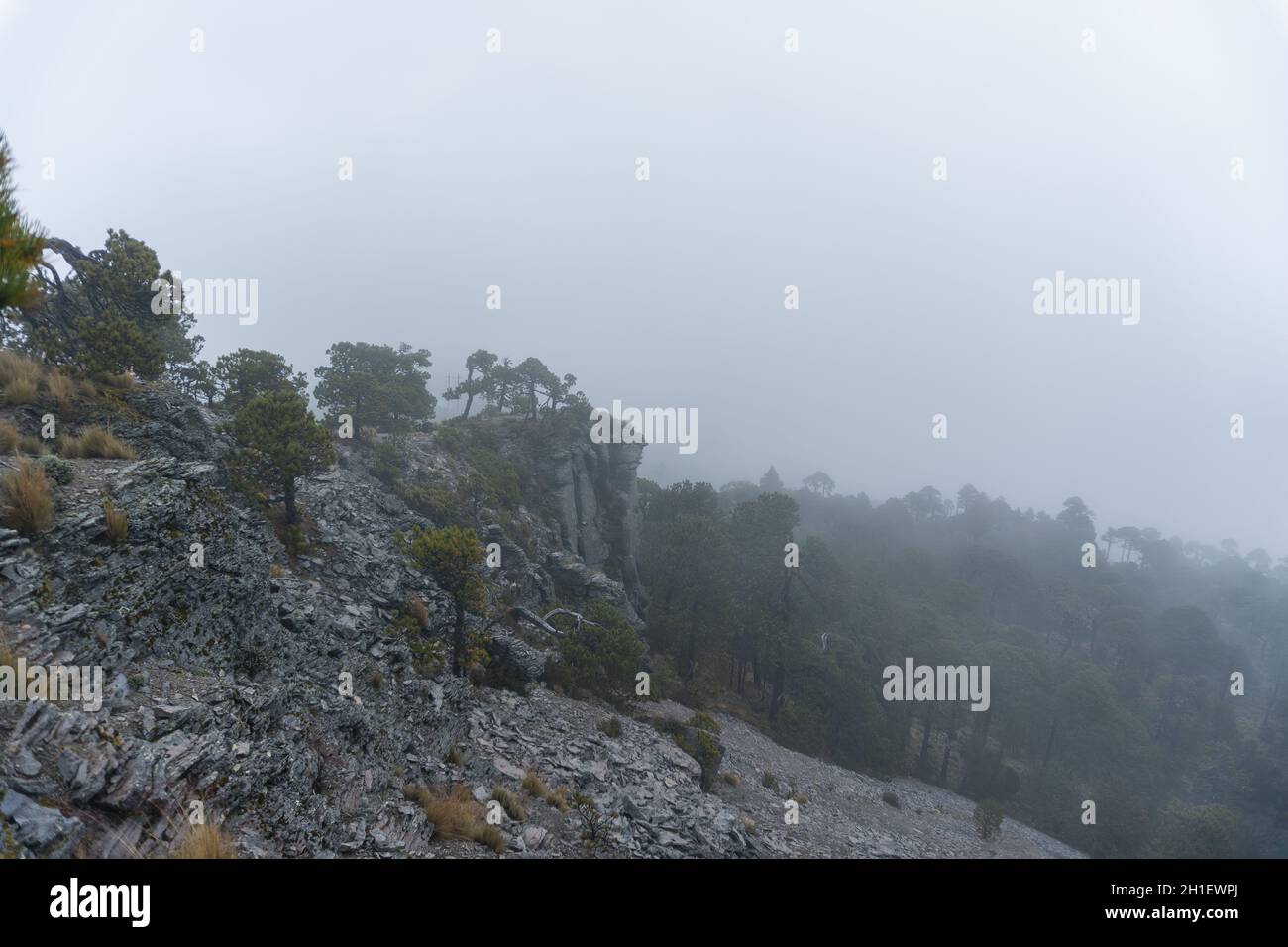 Low angle shot of a rocky mountain peak in the fog Stock Photo - Alamy