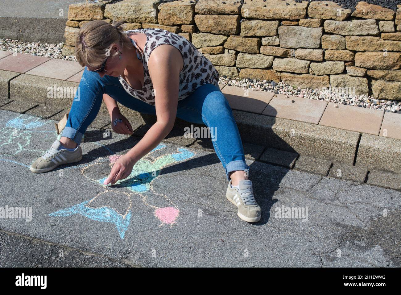 Drawing of a young woman with Kreide on Asphalt malt. Konzept Kreativität auf grauer Straße, auf Asphaltbürgersteig Außentätigkeiten für Künstler. Dra Stock Photo