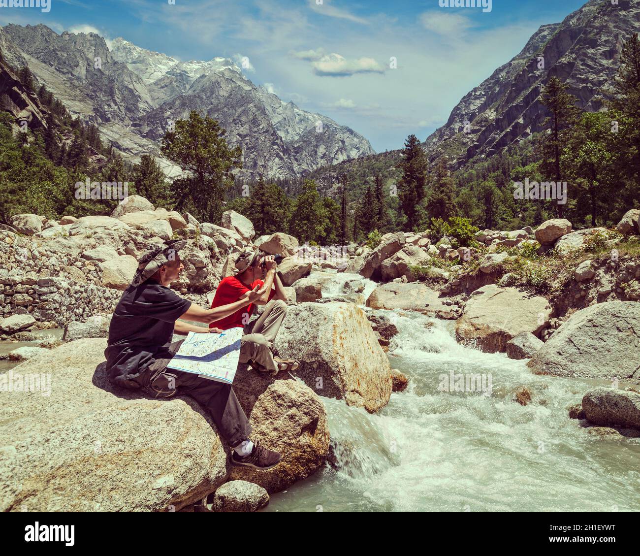 Vintage retro effect filtered hipster style image of hiker trekker tourists read a trekking map on trek in Himalayas mountains. Himachal Pradesh,India Stock Photo