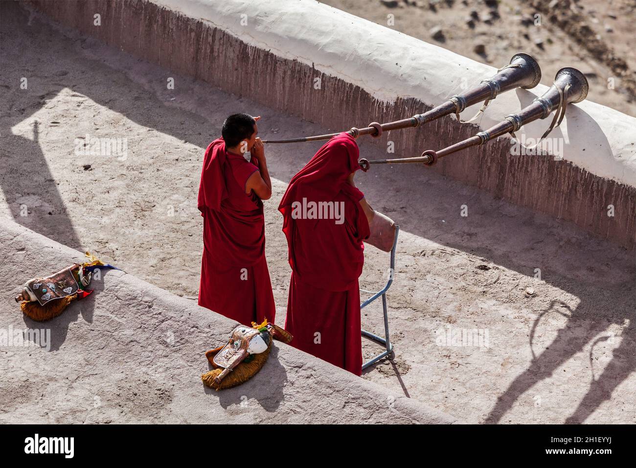 THIKSEY, INDIA - SEPTEMBER 4, 2011: Two Tibetan Buddhist monks blowing Tibetan horn (dungche) during morning pooja, Thiksey gompa, Ladakh, India Stock Photo