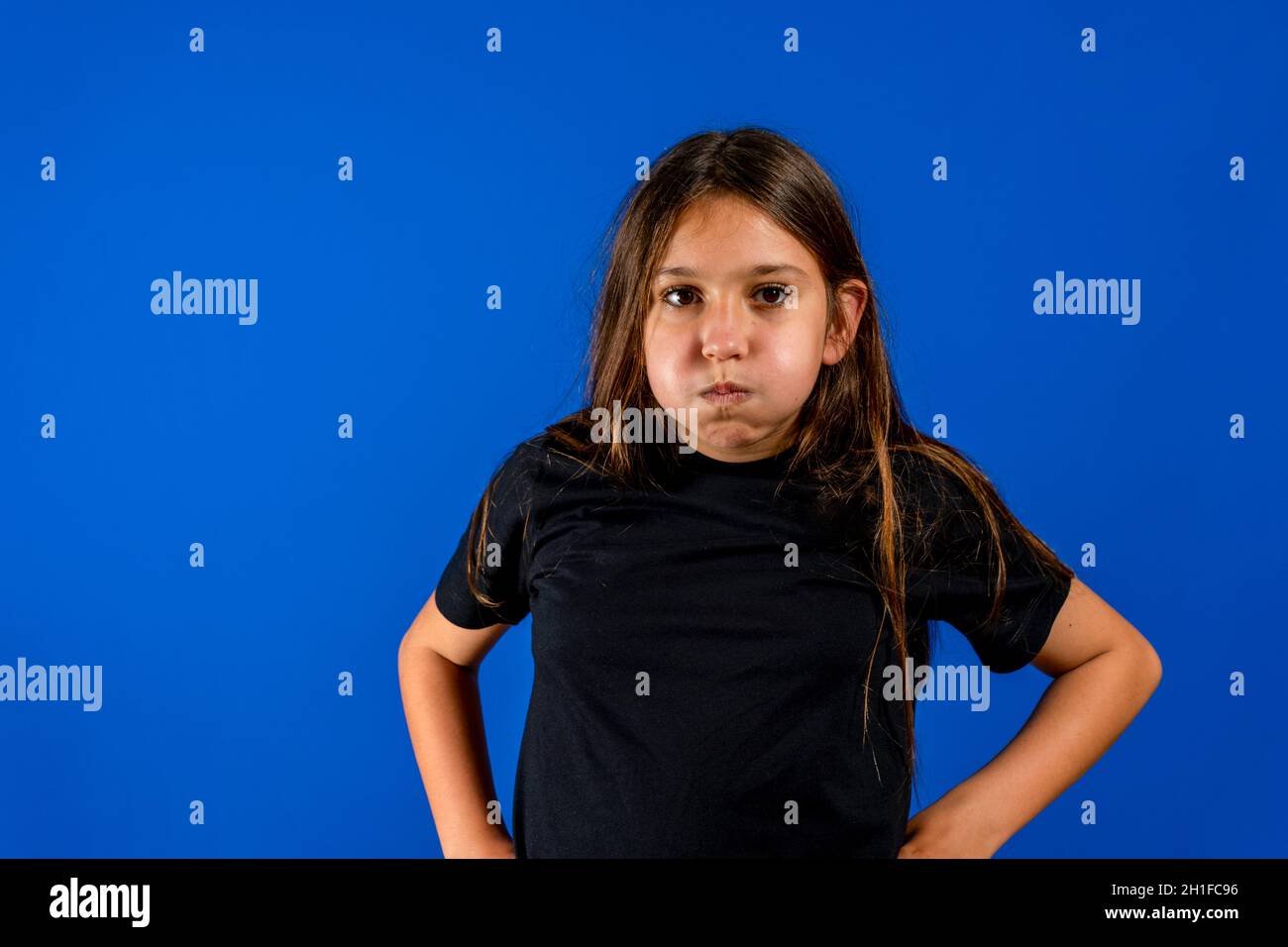The little girl puffed out his cheeks isolated on blue studio background. Gesture concept Stock Photo