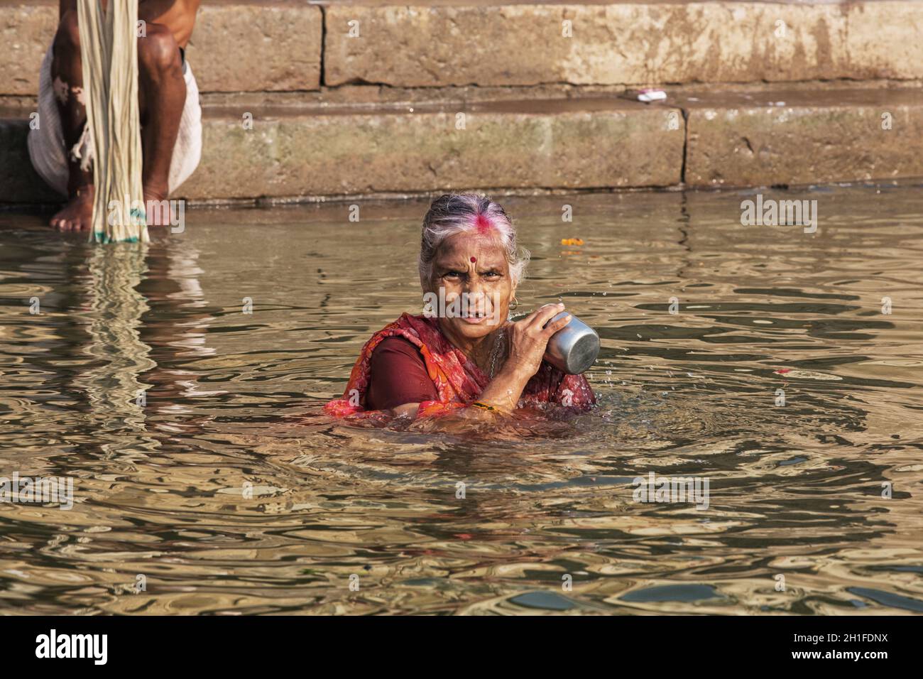 Unidentified Hindu woman pilgrim take bath in the Holy river Ganges at the ghats of Varanasi, Uttar Pradesh, India Stock Photo