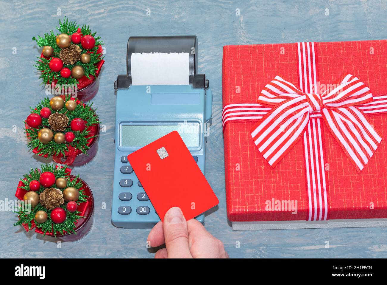Christmas sale. A hand holding a red bank card above the cash register