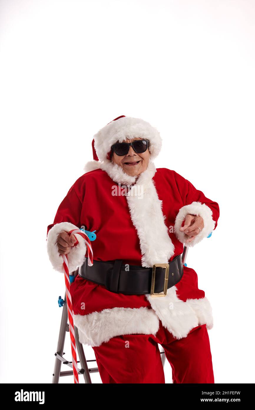A nonagenarian in a Santa Claus costume laughing and sitting on a walker. Stock Photo
