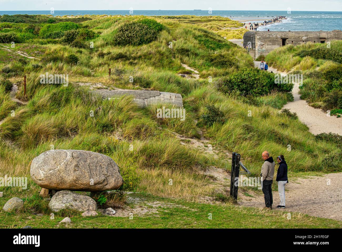 Tourists on the sandy path to the Grenen Peninsula observe the tomb of the Danish poet and playwright Holgher Drachmann. Skagen, Denmak Stock Photo