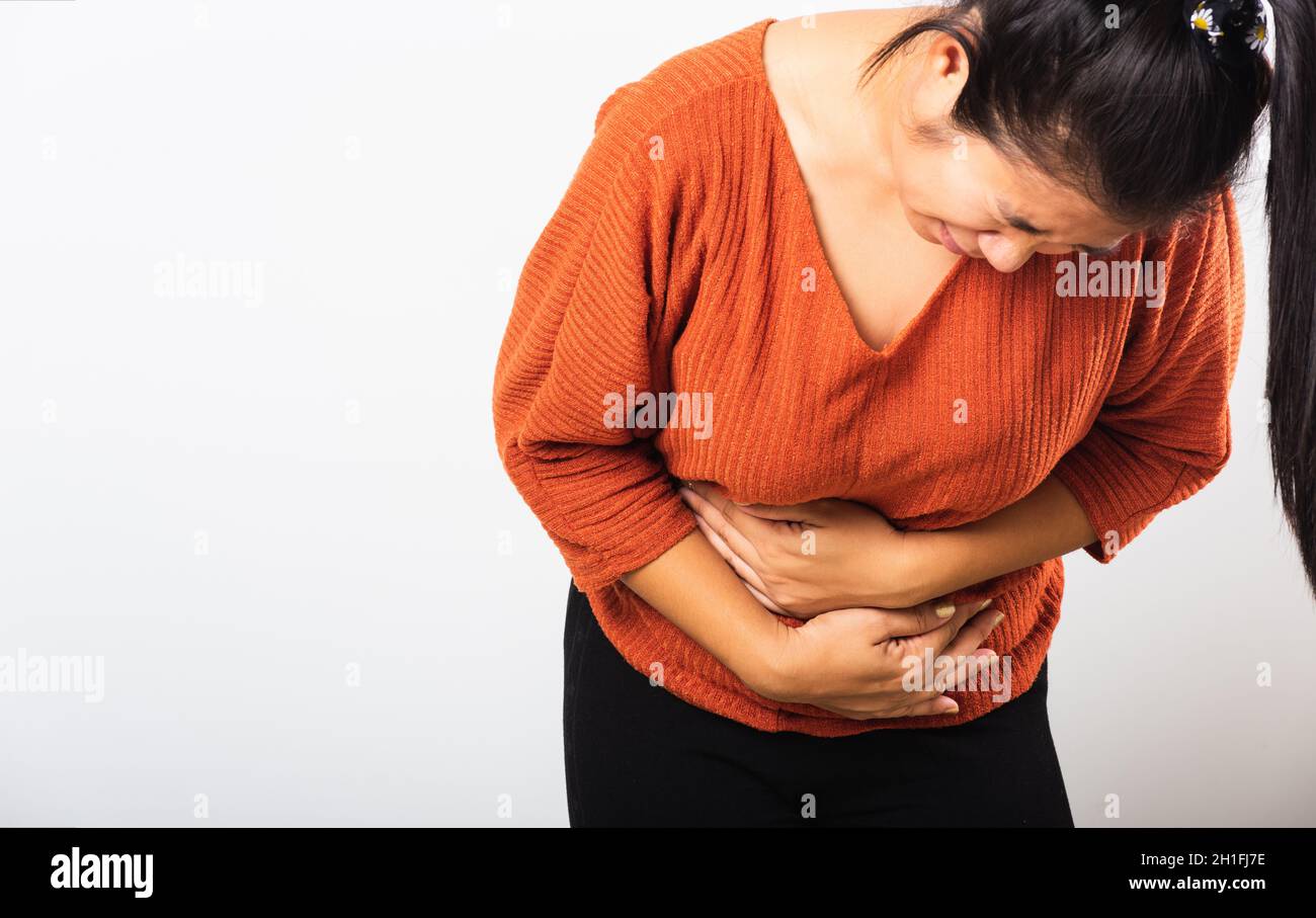 Asian woman she sick have stomach ache holds hands on abdomen, part of body, female having painful stomachache she abdomen bloating or chronic gastrit Stock Photo