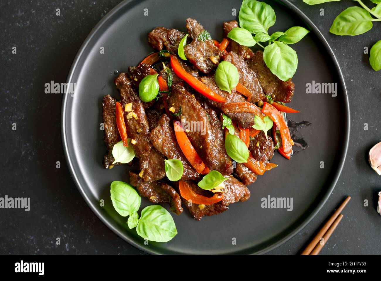Thai beef stir-fry with pepper and basil on plate. Top view, flat lay Stock Photo