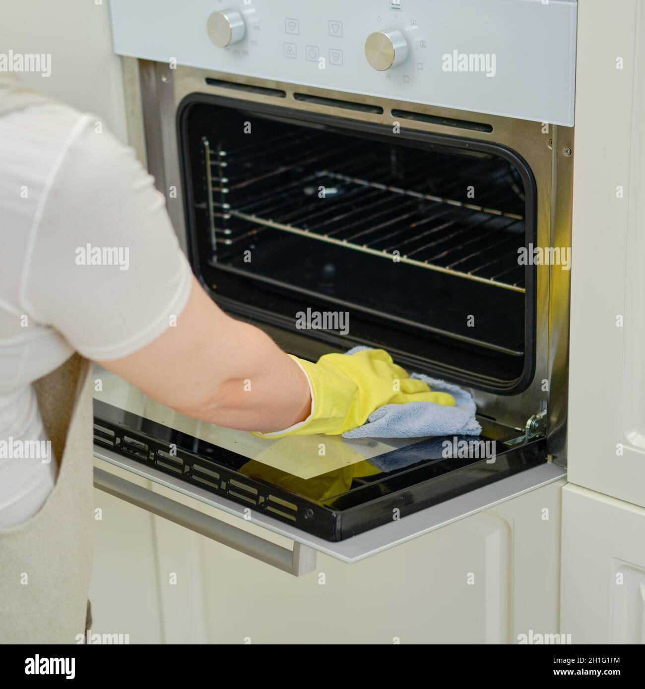 A woman wipes an electric oven with a rag when cleaning a home kitchen ...