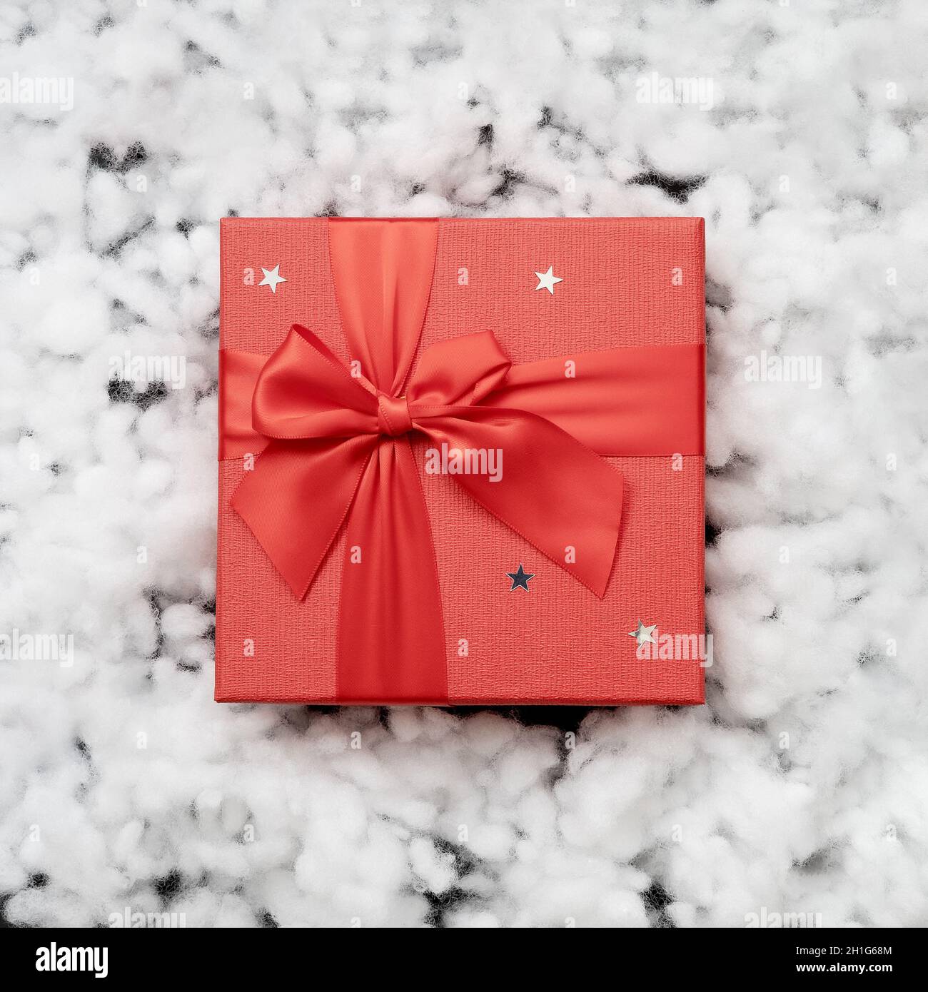 A red gift box in the middle of white fake fiberfill snow. Top view ...