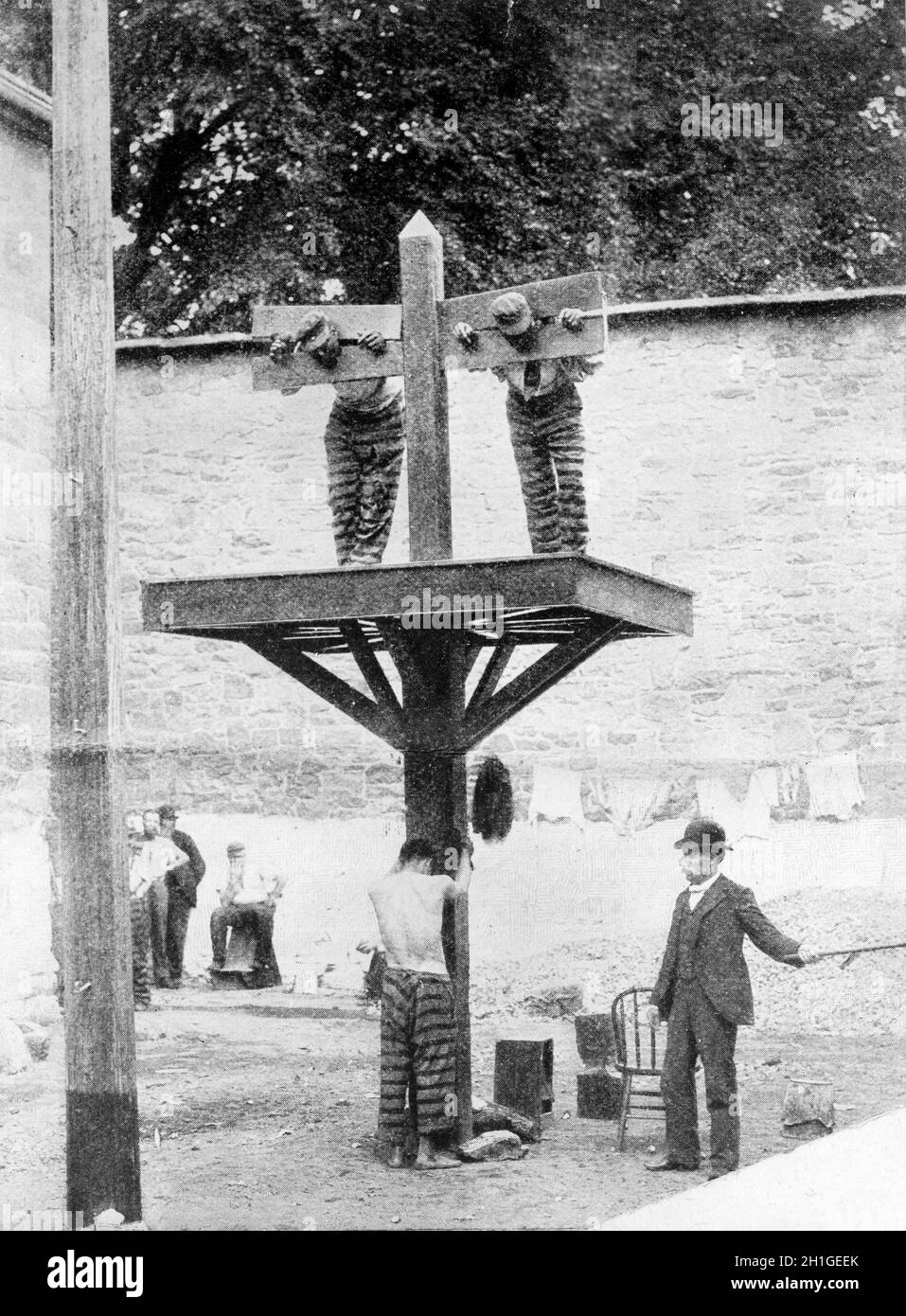 Two prisoners in pillory with another tied to whipping post below and a man with whip, at New Castle County Courthouse in Delaware, America Stock Photo
