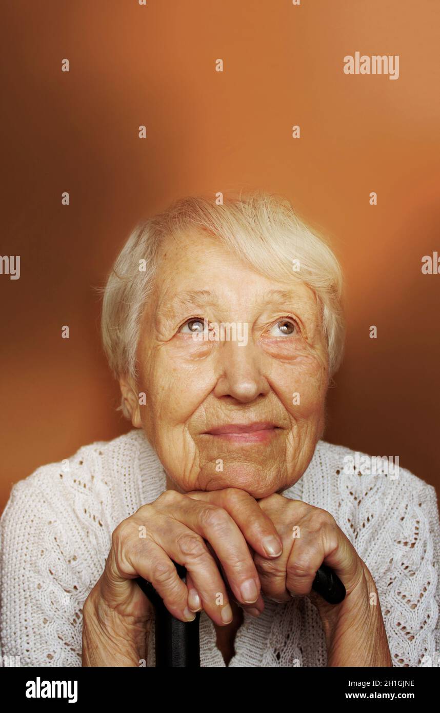 Smiling senior woman relaxing In chair holding walking stick or cane. Hope and dreams concept Stock Photo