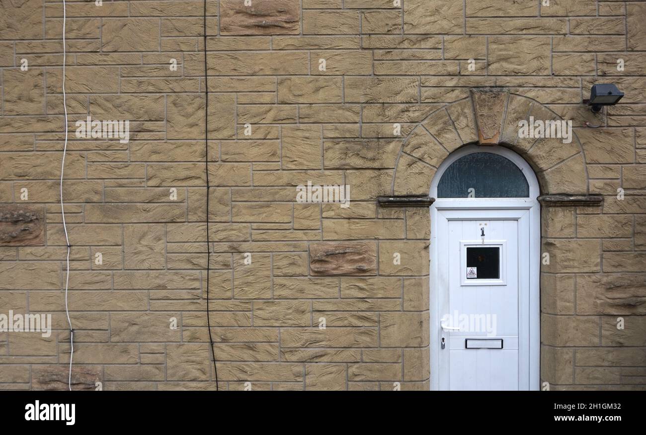 Victorian brick terrace house, clad in fake stone tiles, with a plastic UPvc door.  An awful example of bad DIY work spoiling an old house. Stock Photo